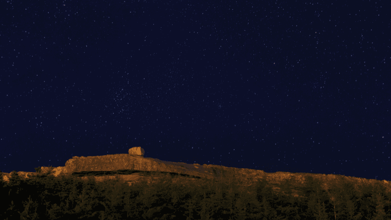 The starry night sky shines over the mountains in L'Anse au Clair.