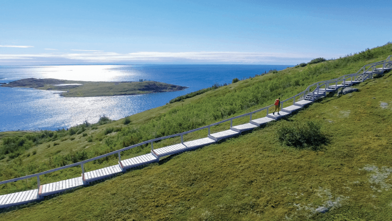 A traveller hiking the boardwalk that overlooks the ocean in Red Bay.