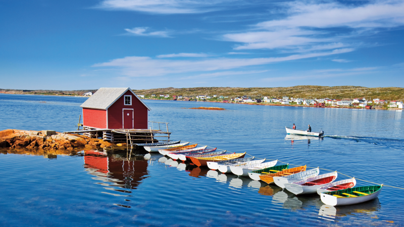A row of colourful boats leads to a red fishing shed in the middle of the water in Joe Batt’s Arm, Fogo Island.