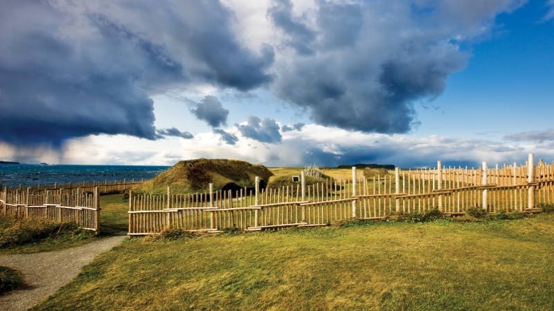 A wooden fence surrounds the ancient Viking settlement of L’Anse aux Meadows National Historic Site.