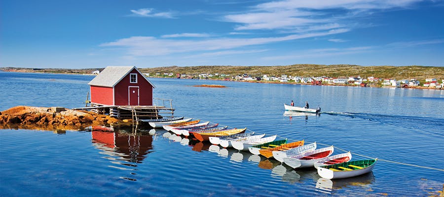 A row of colourful boats leads to a red fishing shed in the middle of the water in Joe Batt’s Arm, Fogo Island.