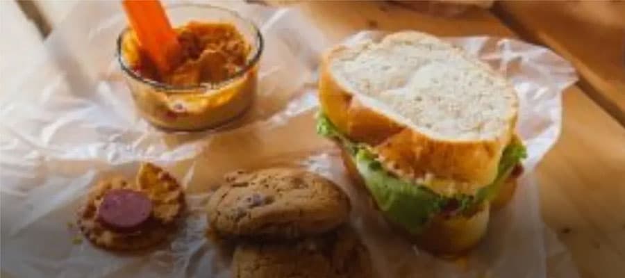 A row of colorful three-story houses with white trim. From left to right, the houses are green, red, blue, and yellow. The sky is partly cloudy, and power lines run across the scene.
