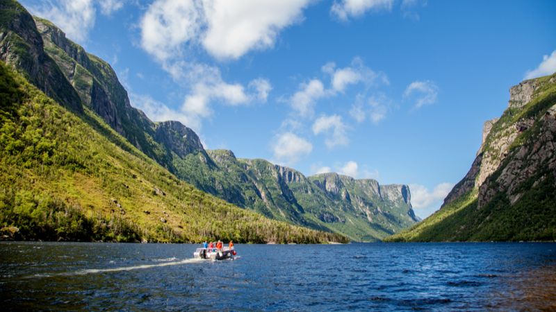 A tour boat is cruising through Western Brook Pond Fjord in Gros Morne National Park.