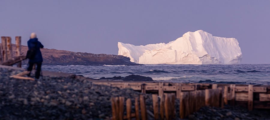 A traveller photographing an iceberg from the shoreline.