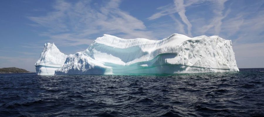 A giant iceberg standing tall near the coastline.